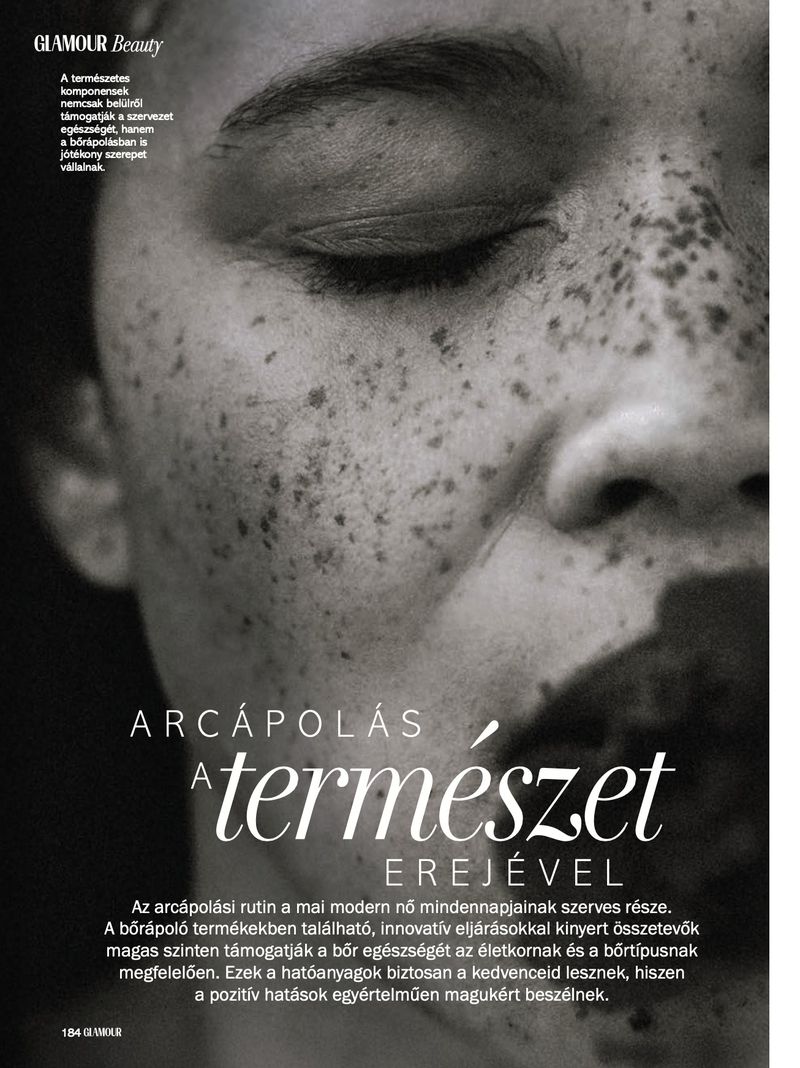 Monochrome close-up of a woman's face with freckles and dark lipstick, as seen in a magazine ad for Glamour Beauty.