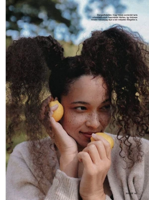 Woman with long dark curly hair holding lemons near her face in an editorial beauty shot for Glamour Hungary