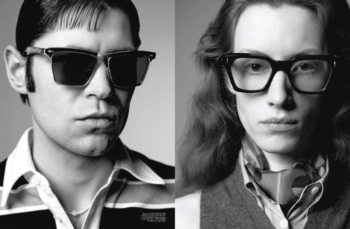 Close-up portrait of two models wearing dark sunglasses and patterned clothing against a neutral studio background.