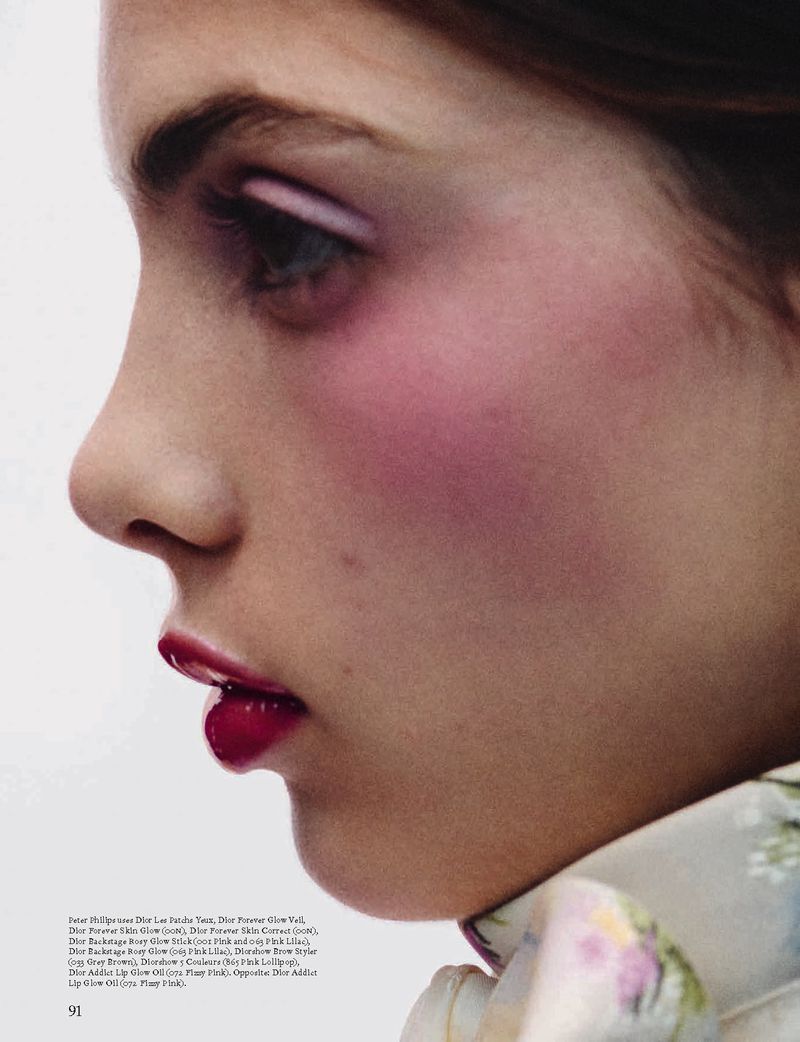 Close-up profile of a woman with bold pink makeup on her eyes and cheeks, paired with a deep red lipstick. Soft lighting on pale skin.