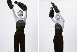 Model Marylore Heck in a black strapless top with dramatic ruffled arm accessories posing against white seamless for Dazed Magazine.