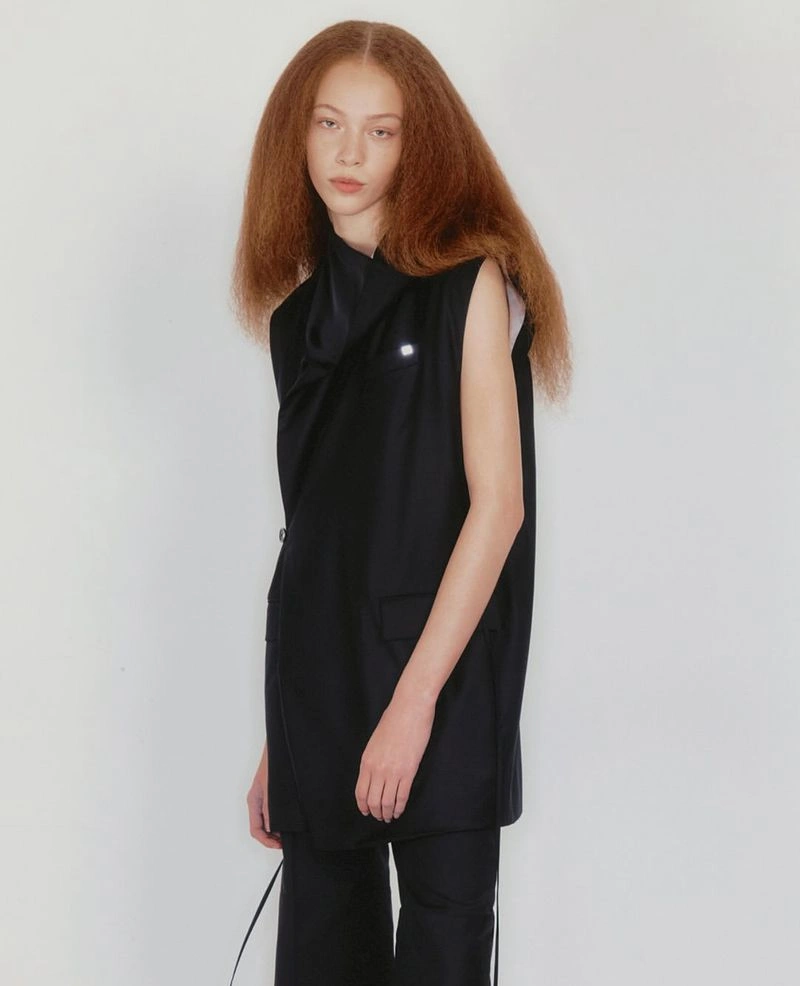 Model with long reddish hair wearing a black sleeveless top against a plain white background for Helmut Lang Pre-Fall 2025 lookbook
