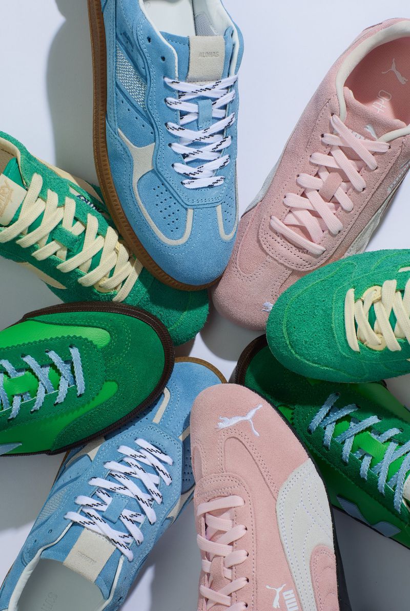 Pile of stylish Puma and Diadora suede sneakers in green, pink, and light blue with white laces displayed on a white background.