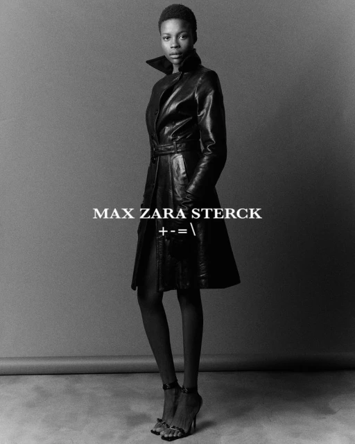 Black and white portrait of a dark-skinned woman in a leather coat and heels, posing in front of a plain background. Fashion editorial.