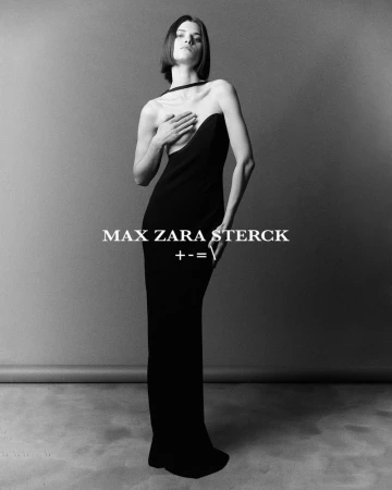 Model wearing a long black strapless dress posing against a grey seamless studio backdrop in a black and white fashion portrait.