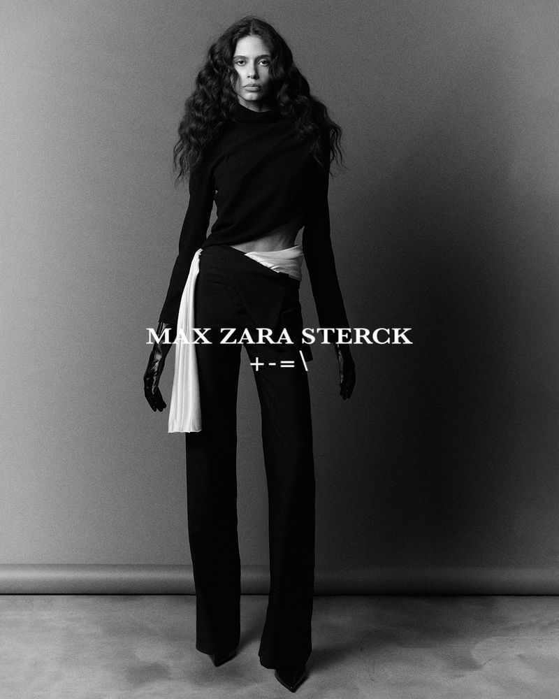 Elegant fashion portrait of a woman in black clothing with long wavy hair, standing in front of a grey backdrop with overlaid text.