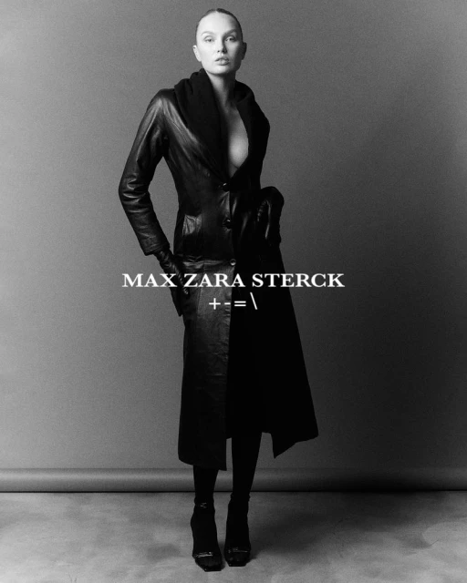 Elegant studio shot of a slender fashion model in a black leather coat, dark stockings, and high heels against a gray backdrop.