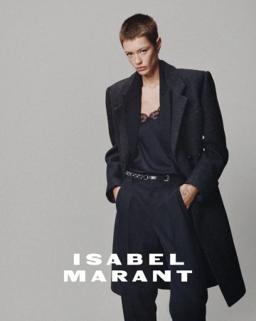 Model with short buzzcut wearing a dark wool coat and trousers against a neutral grey seamless background