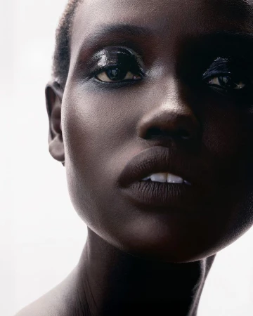 Close-up beauty portrait of a Black woman with glossy dark eye makeup against a bright white background for Tom Ford Beauty