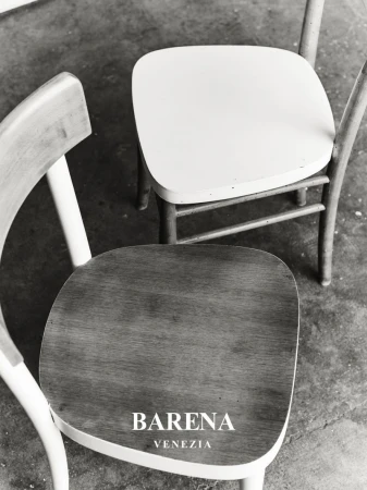 High-angle shot of two minimalist wooden chairs in a black and white photograph, featuring the brand name BARENA VENEZIA.