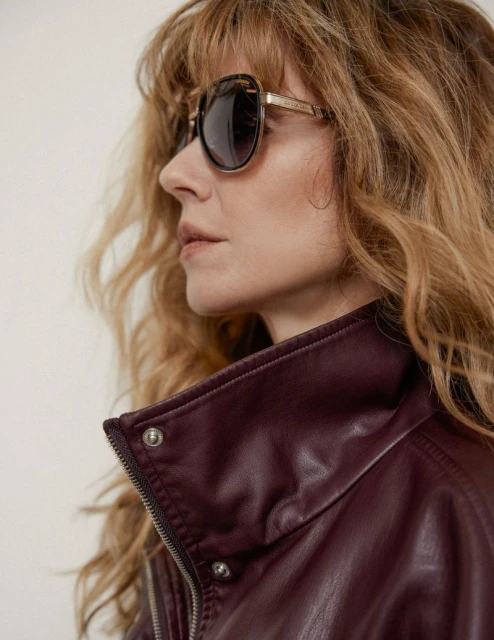 Portrait of a woman wearing sunglasses and a burgundy jacket, showcasing fashion style and attention to detail.