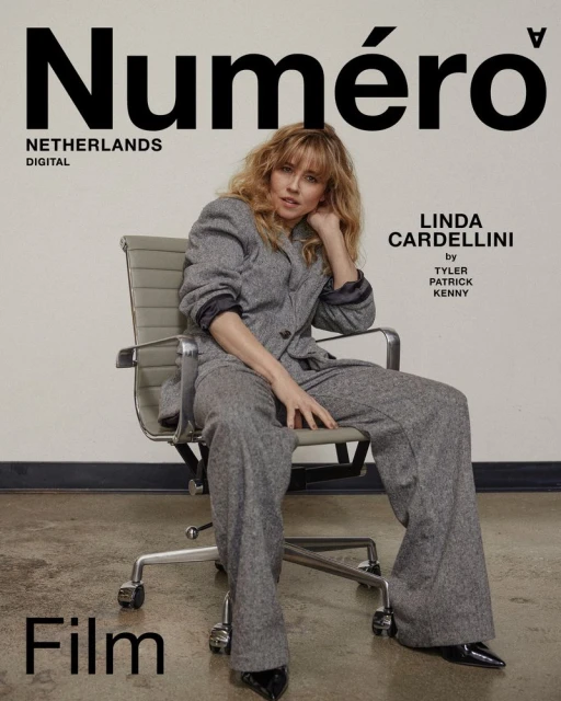 Linda Cardellini poses on an office chair for a Numéro Netherlands magazine cover, wearing a grey suit and black heels, with minimal makeup.
