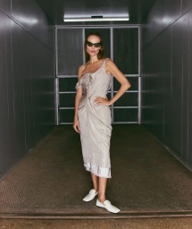 Model Natasha Poly wearing a silver dress and white loafers inside a metallic freight elevator for 72 Magazine