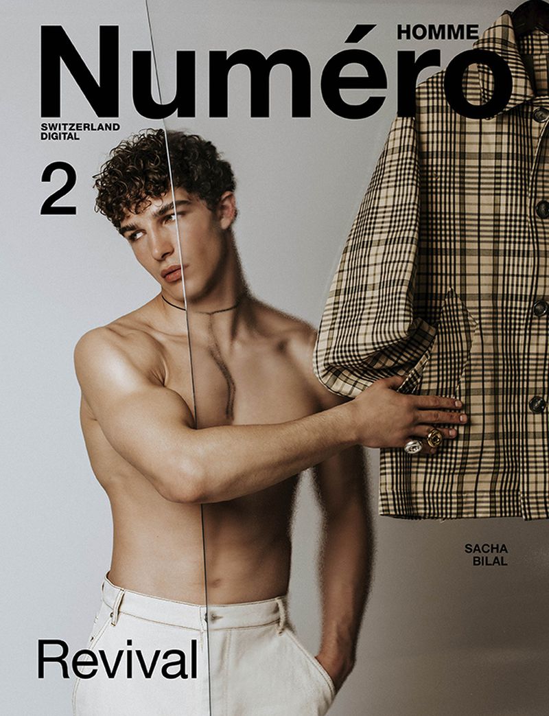 Magazine cover featuring a shirtless male model and a plaid jacket, presenting a modern and stylish editorial image with clear typography.