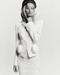Model Mona Tougaard wearing a white structured jacket and cap against a plain white background for CR Fashion Book.