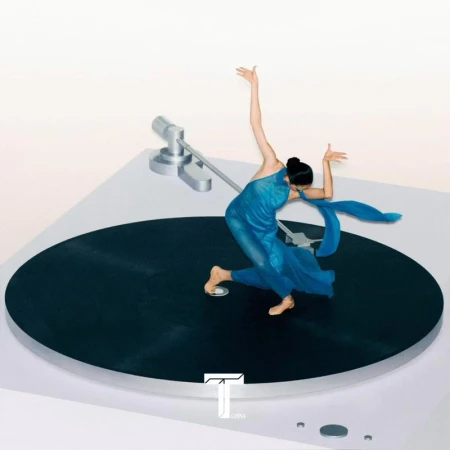 A dancer in a blue dress poses elegantly on a black turntable platform against a clean white background in a stylized fashion shot.