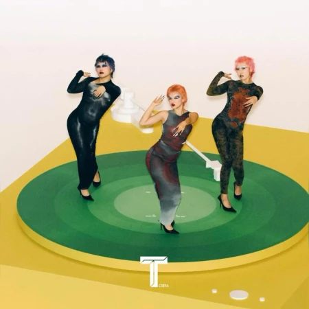 Three women strike a pose on a giant green turntable against a bright yellow and white background, showcasing fashion and music.