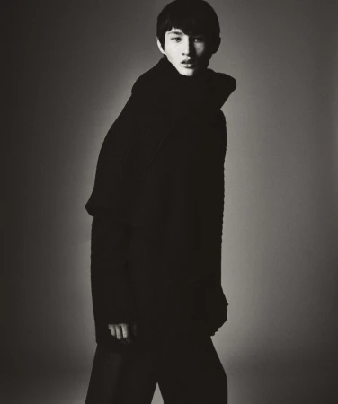 Young man in dark high-neck winter sweater standing against a gradient studio backdrop for HERO Magazine.