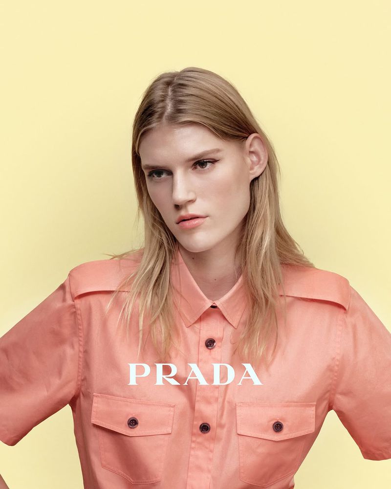 Model wearing a pink button-down shirt against a matching yellow backdrop for Prada Beauty, photographed by Fiona Torre.