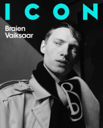 Monochrome portrait of male model Braien Vaiksaar wearing a light jacket and dark scarf against a shadowed wall for ICON Magazine France