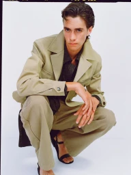 Model Marcelo Mendez crouching in a beige suit jacket and trousers against a white backdrop for Recto SS26 Mens