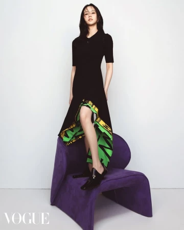 A fashionable young woman poses in a black dress on a purple chair against a white backdrop in a studio shot.