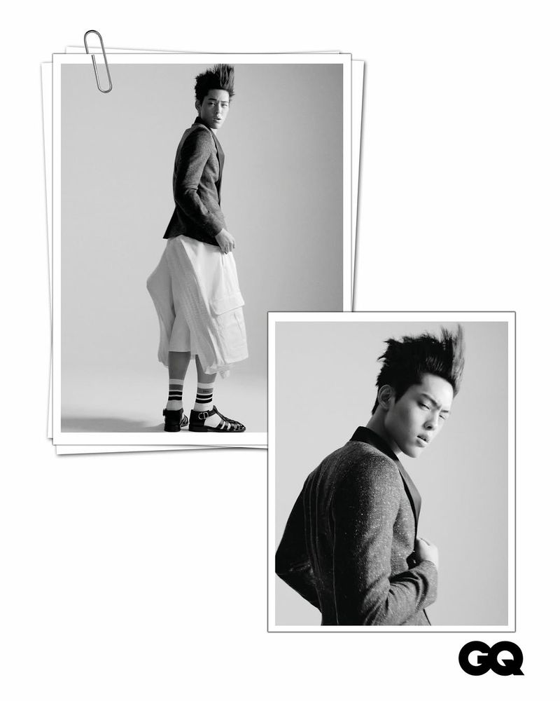 Black and white fashion portrait of an adult male model wearing a blazer and culottes in a photo studio pinned to paper.