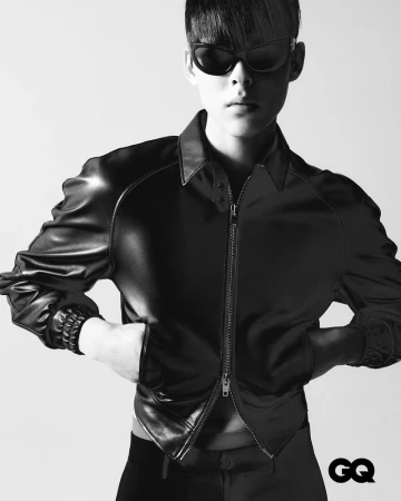 Black and white portrait of a young Asian man wearing a black leather jacket and dark sunglasses against a neutral background with GQ logo.