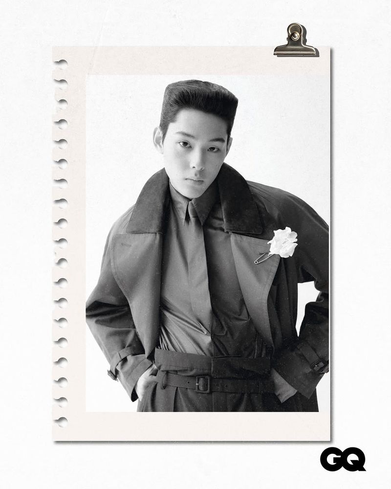 A black and white portrait of a young adult in a vintage-style coat and shirt, pinned to a notepad, with the GQ logo in the corner.