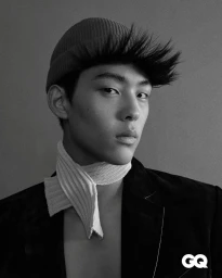 Monochrome portrait of a young man wearing a beanie, knitted scarf, and dark jacket against a plain background.
