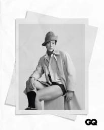 Man wearing a textured hat and trench coat seated in a studio setting for GQ Hong Kong