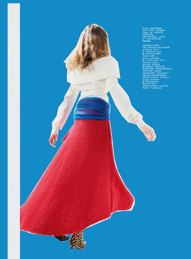 Fashionable woman with long hair and red skirt poses against vibrant blue backdrop, showcasing editorial style in a studio setting.