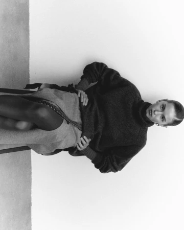 Model wearing a dark turtleneck sweater seated against a plain background for an Elle Kazakhstan fashion editorial project.