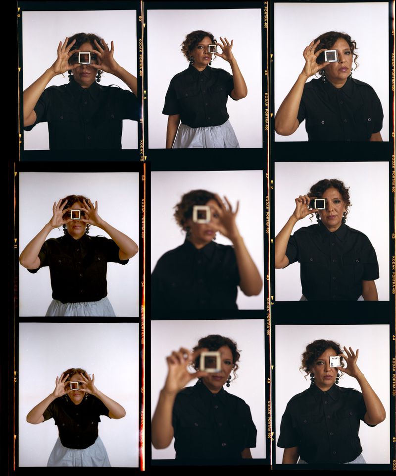 Filmstrip of an adult woman in black shirt, posing with a photographic slide in front of her eye, set against a white background.