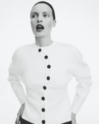 Model wearing a white cardigan with large black buttons against a plain white background for Zara project The New.