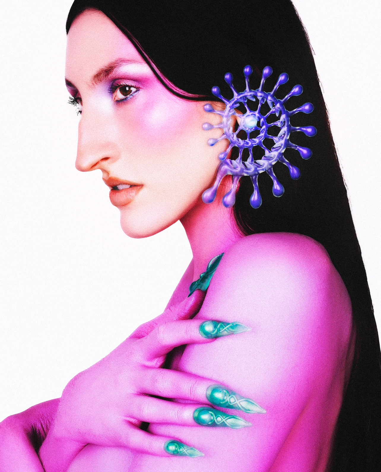 Conceptual beauty portrait of a fair-skinned woman in profile with elaborate makeup, surreal jewelry, and long dark hair against a white background.