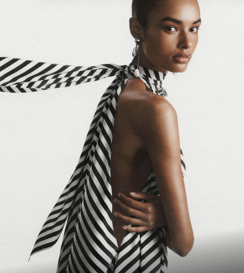 Striking studio shot of a woman with dark hair and fair skin in a black and white striped dress, gazing intently at the camera.