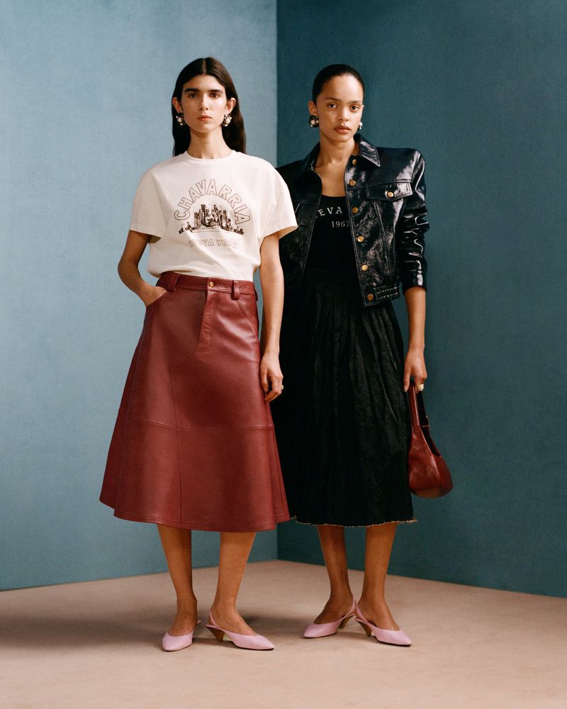 Two adult females model retro fashion against a teal wall, showcasing a t-shirt, leather skirt, jacket, dress, purse and pink slingbacks.