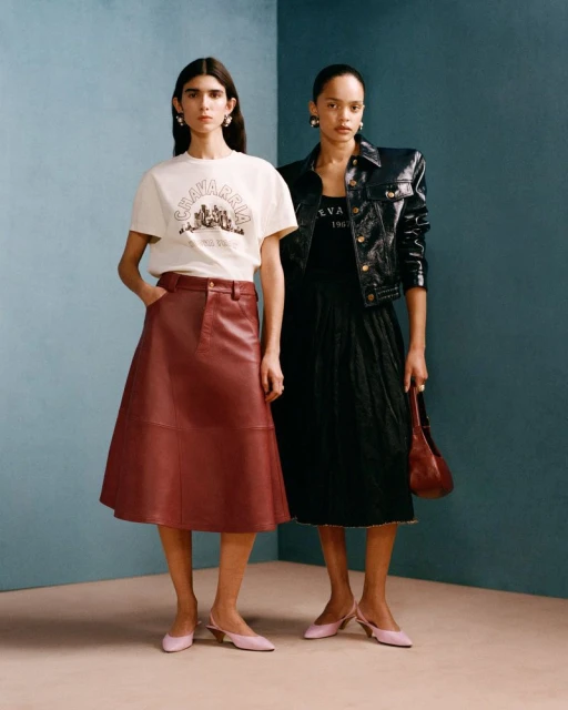Two adult females model retro fashion against a teal wall, showcasing a t-shirt, leather skirt, jacket, dress, purse and pink slingbacks.