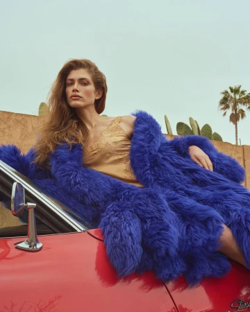 Model Valentina Sampaio in blue faux fur coat lying on red car for Harper's Bazaar Greece