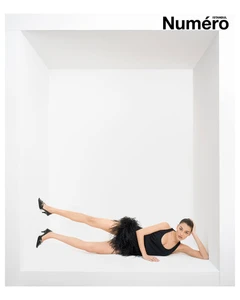 Woman in a black feather dress lying inside a white architectural alcove