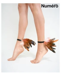 Close-up of bare legs and feet wearing feathered ankle cuffs against a white seamless background with Numéro Istanbul logo.