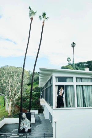 Gabriel Aubry standing on a white modern building balcony next to tall palm trees for Numero Netherlands