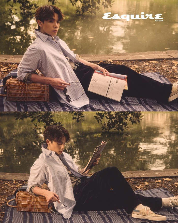 A man in a striped shirt and dark trousers reclining outdoors on a blanket near water for an Esquire Malaysia editorial.