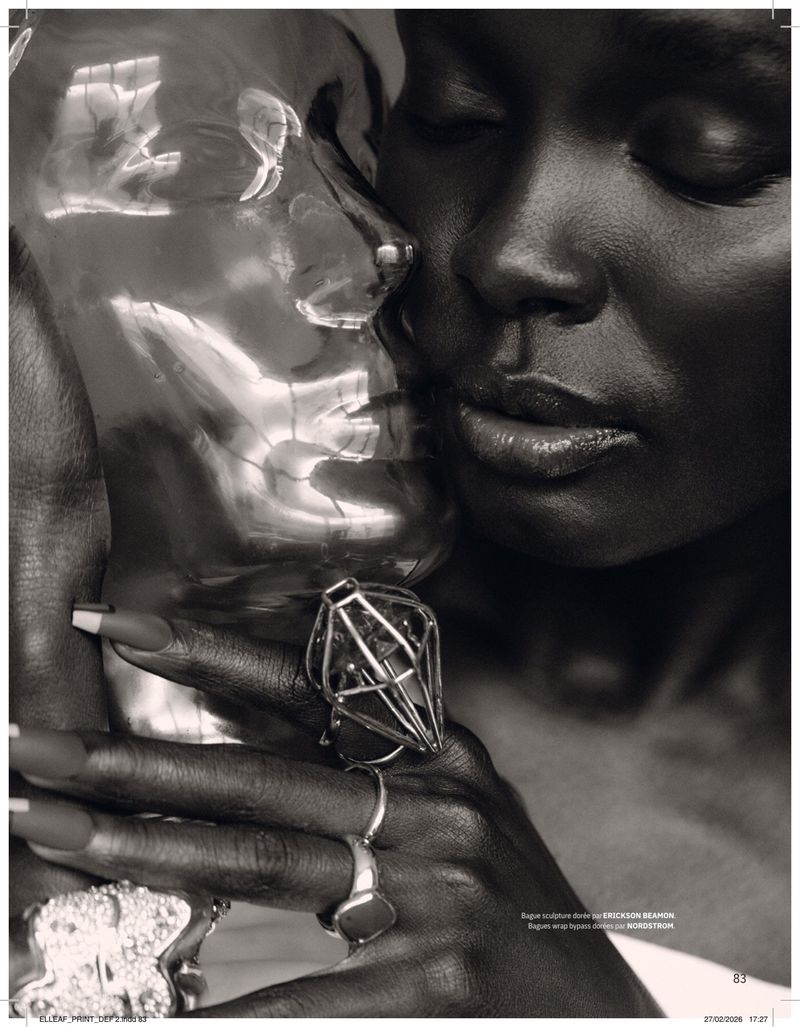 Dramatic close-up of a Black woman with a clear sculpture, adorned with statement rings, showcasing fashion and beauty elements.