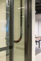 Close-up of a dark metal framed glass door with vertical fluted glass panels and the word HASTINGS printed vertically on the handle.