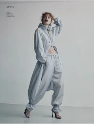 Model wearing a light blue hooded windbreaker and matching drawstring pants against a neutral studio backdrop.