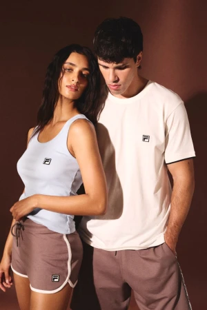 Two models wearing Fila loungewear standing closely against a dark background in a studio campaign portrait.