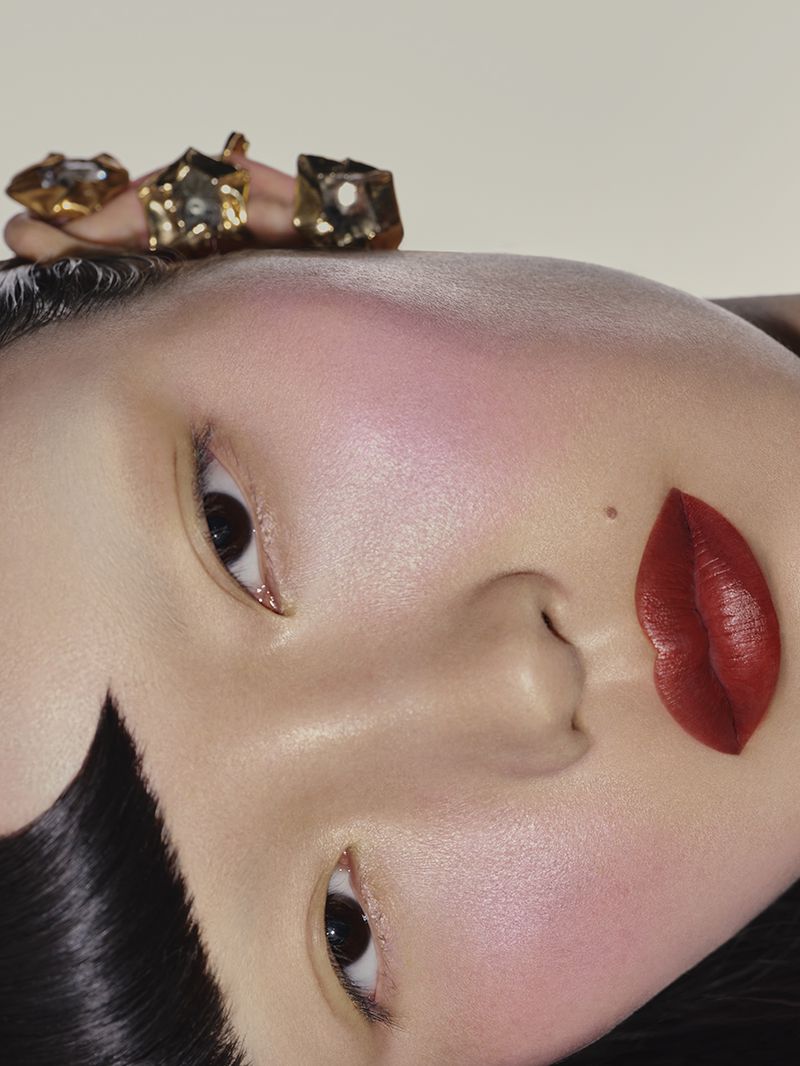 Asian female portrait with red lips and jeweled headpiece against white background. Close-up fashion, makeup, and beauty concept.