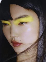 Close-up portrait of a model with bold yellow eyeshadow and glossy lips for Vogue Greece.